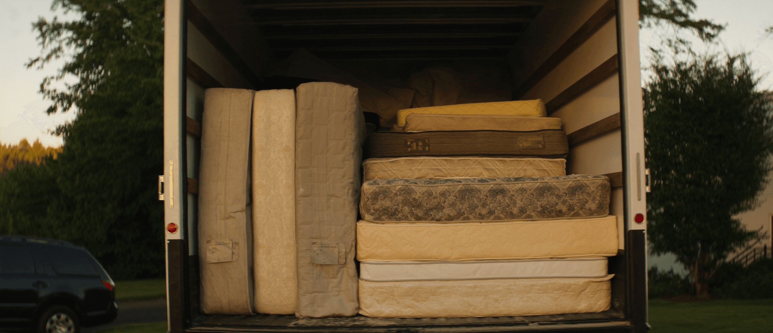Open box truck loaded with mattresses ready for recycling, golden hour